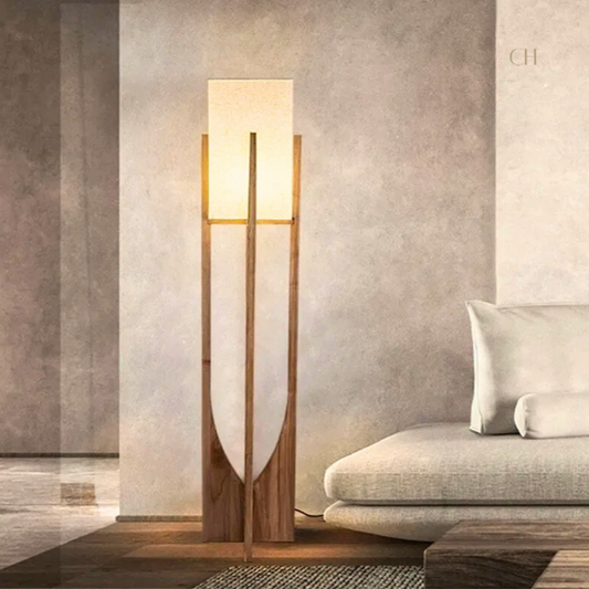 Minari, a floor lamp with a forked wooden base and a cubed linen shade, pictured in a modern living room.