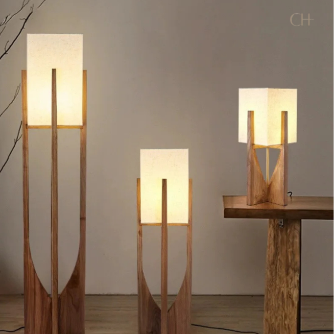 Minari, a collection of lamps featuring forked wooden bases and cubed linen shades. The lamps are set in a minimally decorated room.