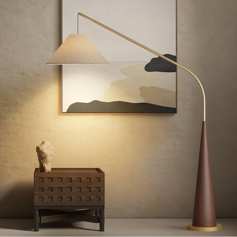 Ellis, a minimalist floor lamp with a brown base and golden arching arm featured in a room.