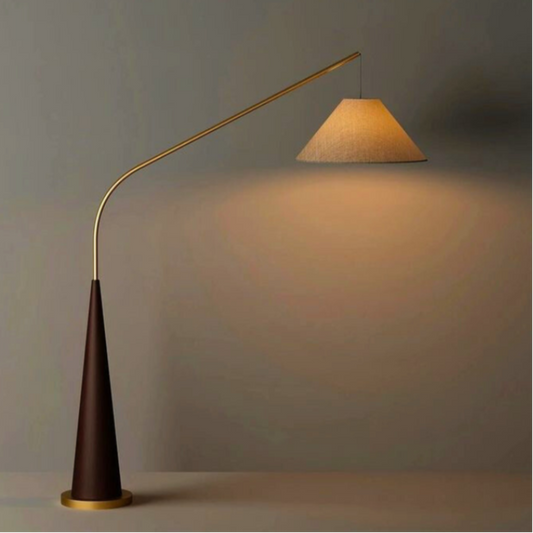 Ellis, a modern floor lamp with brown base and a tapered golden arm in a bare room.