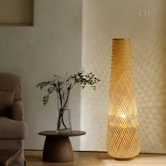 Solace, a cylindrical wicker floor lamp, in a natural light wheat color, pictured in a contemporarily styled living room.
