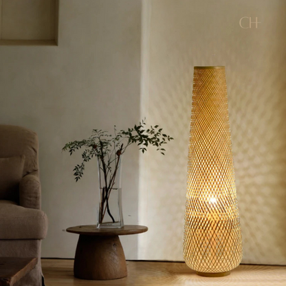 Solace, a cylindrical wicker floor lamp, in a natural light wheat color, pictured in a contemporarily styled living room.