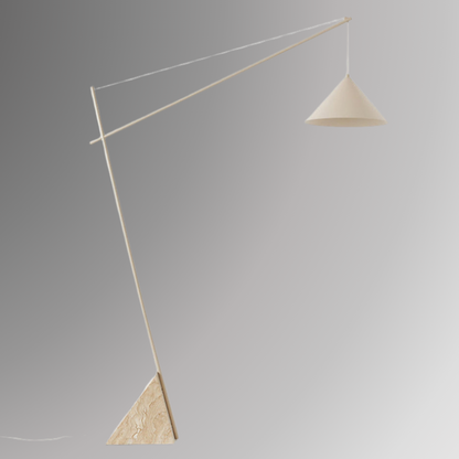 Quentin, a sculptural and minimalist floor light with a beige hued, geometric iron body, and a triangular marble base. Pictured against a greyscale background.