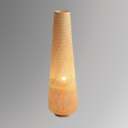 Solace, a cylindrical wicker floor lamp, in a natural light wheat color, illuminated and pictured against a grey scale background.
