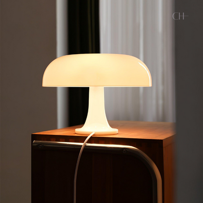 Giancarlo, an ivory colored, artistic, modern table lamp, with a silhouette resembling a mushroom, pictured on top of a wooden counter.