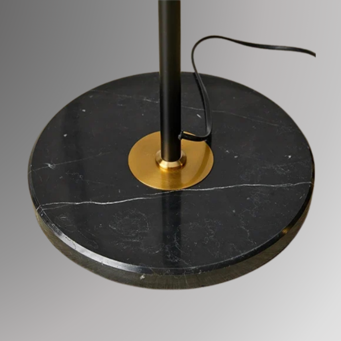 Detailed shot of Ansel's circular base, in black with gold details at the joint with its stem. 