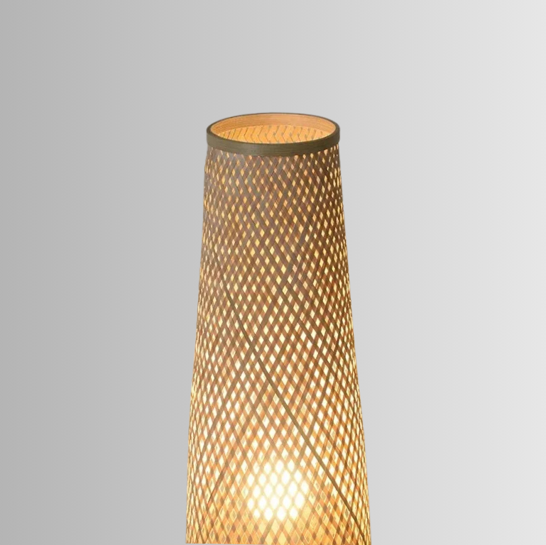 Solace, a cylindrical wicker floor lamp, in a natural light wheat color. The photo is slightly zoomed, focusing more towards the top of the lamp.