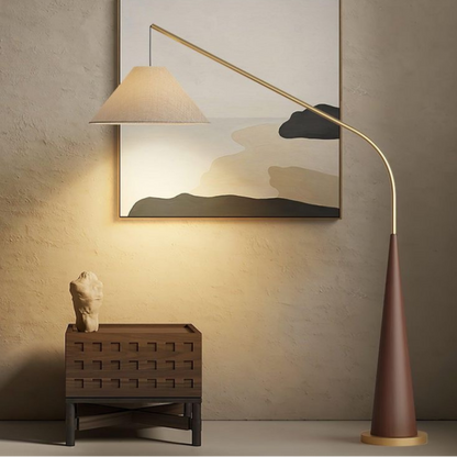 Ellis, a minimalist floor lamp with a brown base and golden arching arm featured in a room.