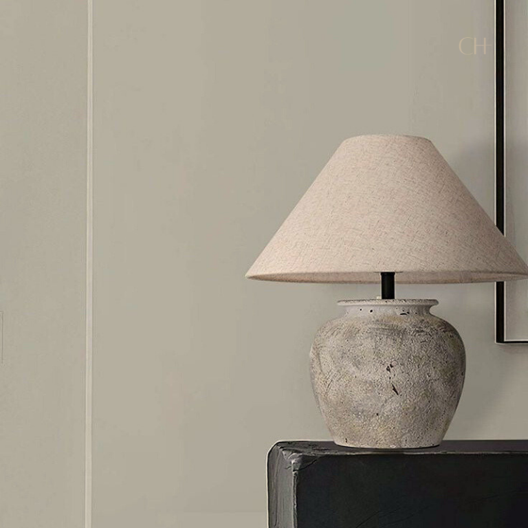 Kaia, a beige toned ceramic table lamp, pictured on a black desk.
