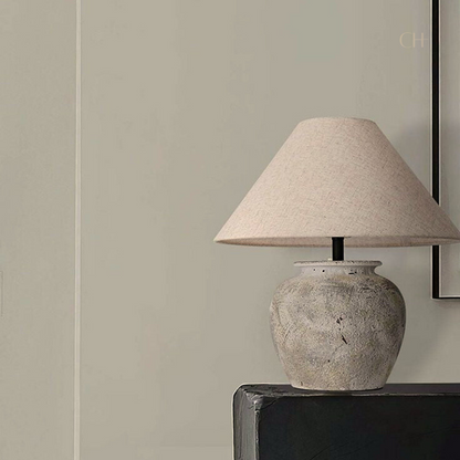 Kaia, a beige toned ceramic table lamp, pictured on a black desk.