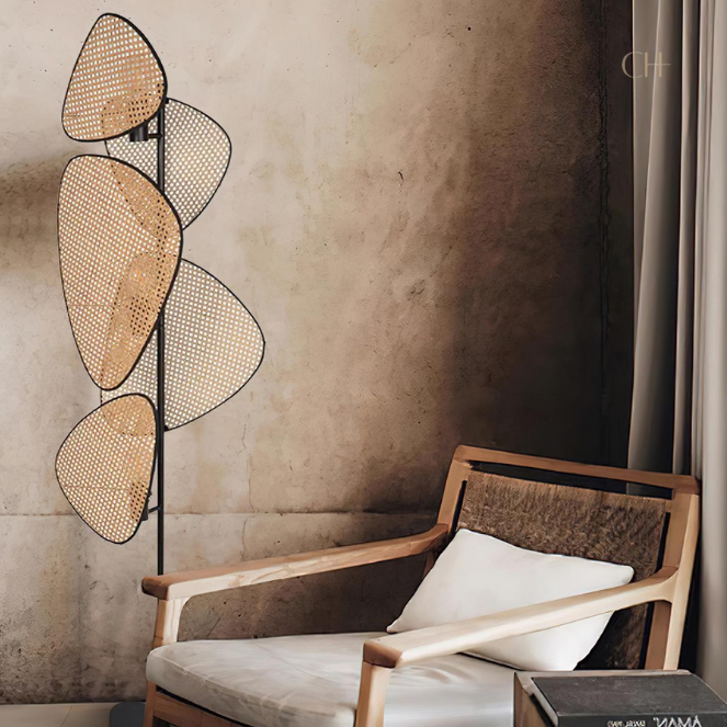 Saray, an iron based floor lamp with 5 leaf shaped wicker shades, pictured in a next to a wooden chair.